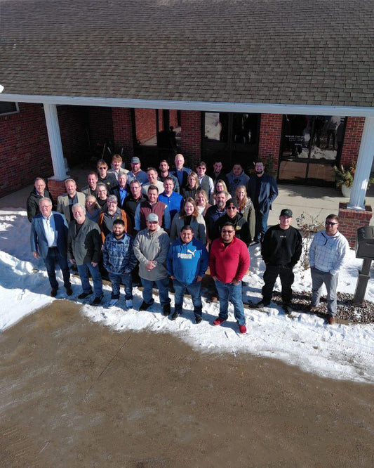 Group of people standing outside a brick building with snow on the ground