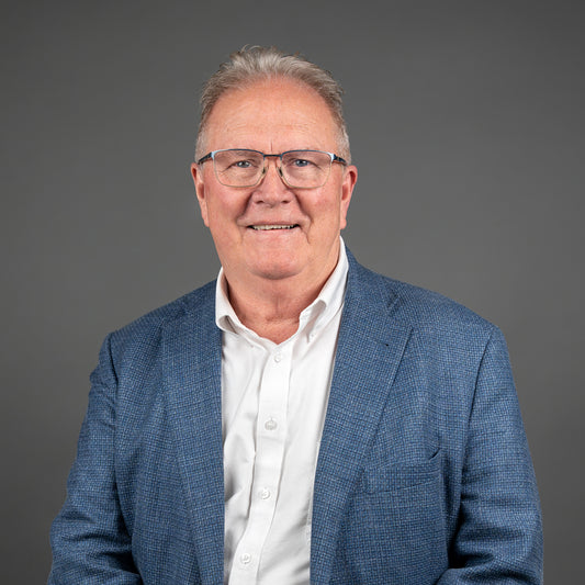 Man wearing a blue blazer and white shirt against a gray background