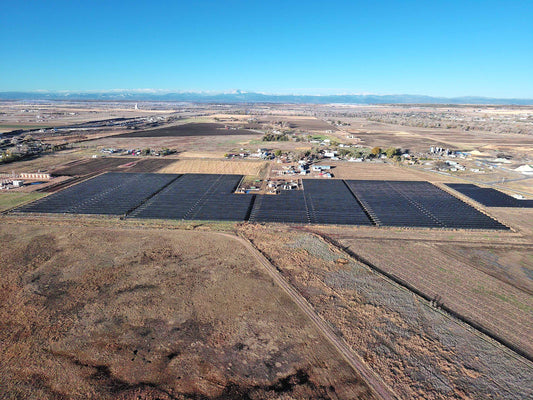 Aerial view of a large solar farm in a rural area with clear blue sky.