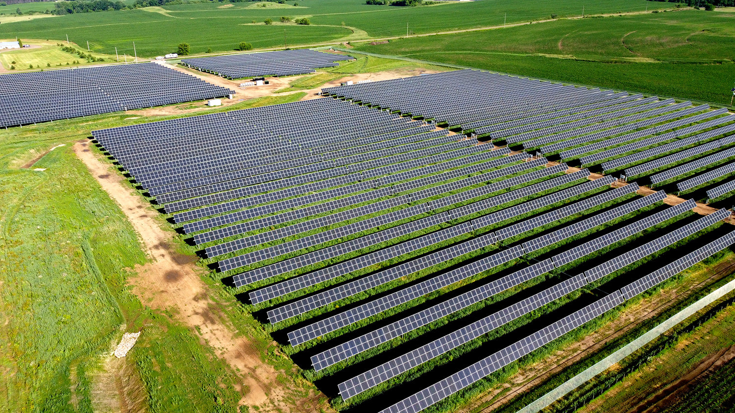 Large solar farm with rows of solar panels on a green landscape