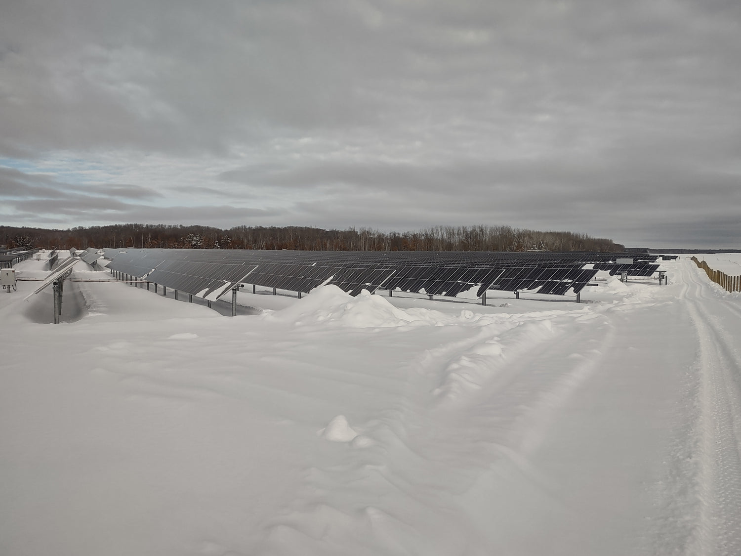 Solar panels on a snow-covered landscape with a cloudy sky.