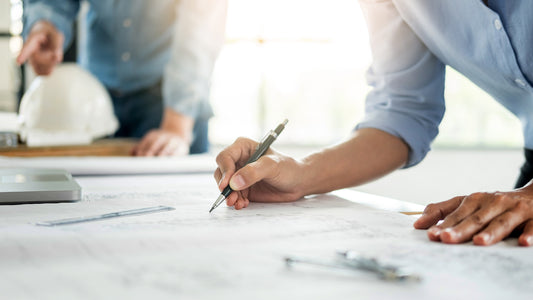 Person working on blueprints with a pen, blurred background