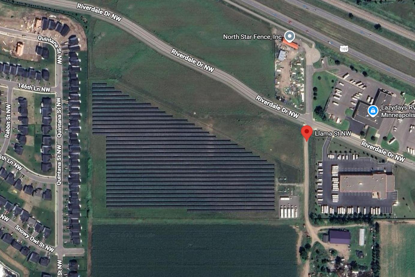 Aerial view of a solar field with roads and buildings surrounding.