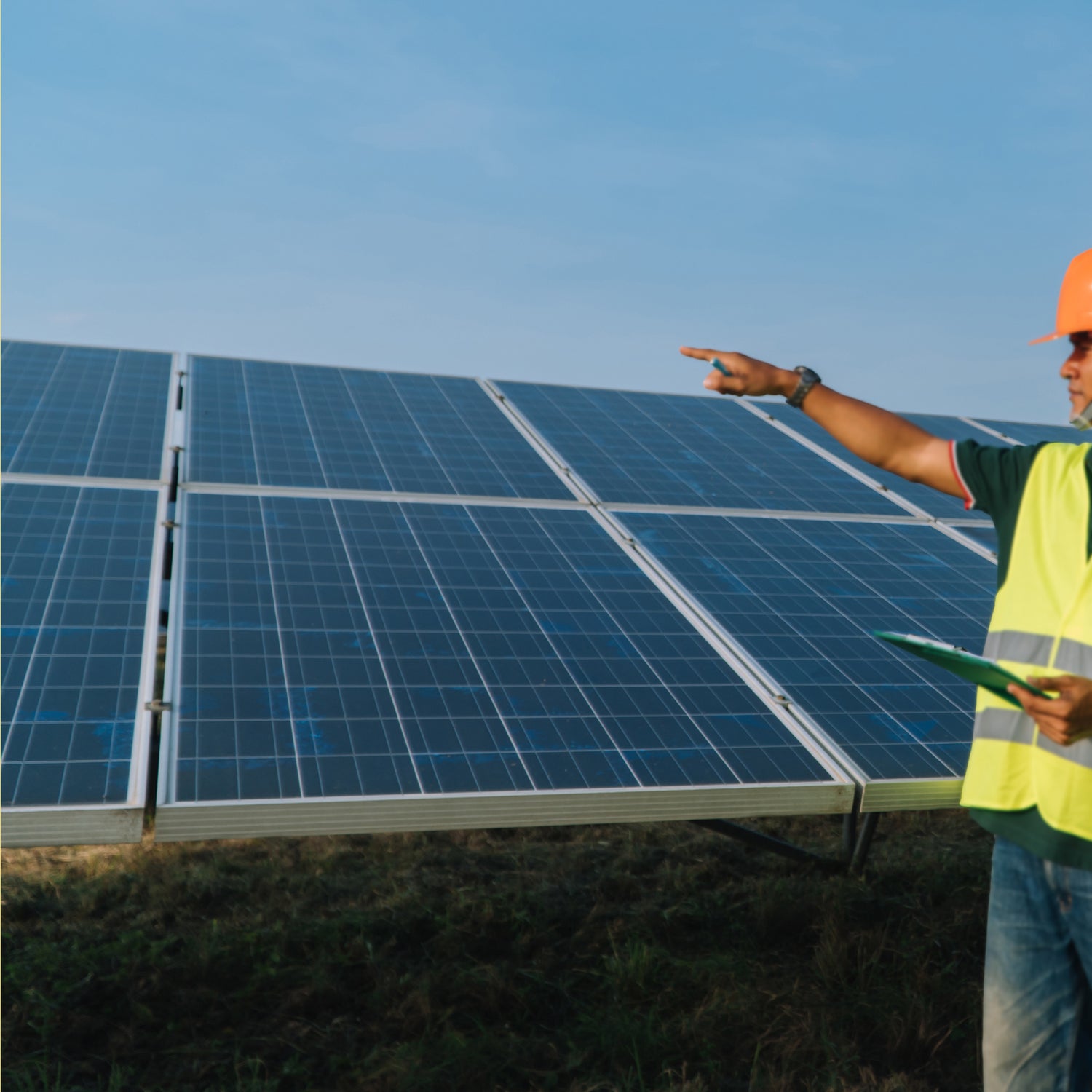 Person in safety gear pointing at a solar panel installation