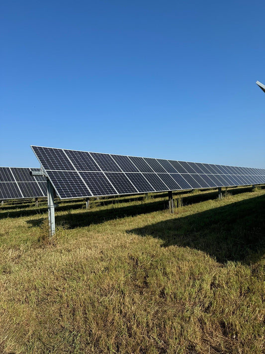 Row of solar panels in a field with a clear blue sky