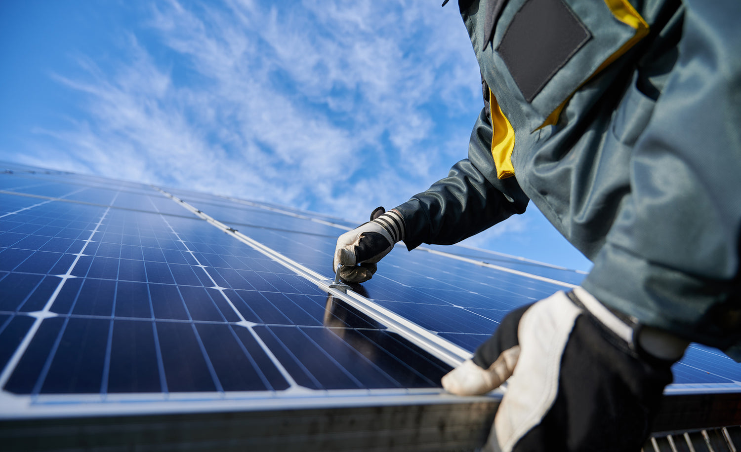 Person cleaning a solar panel with a blue sky in the background