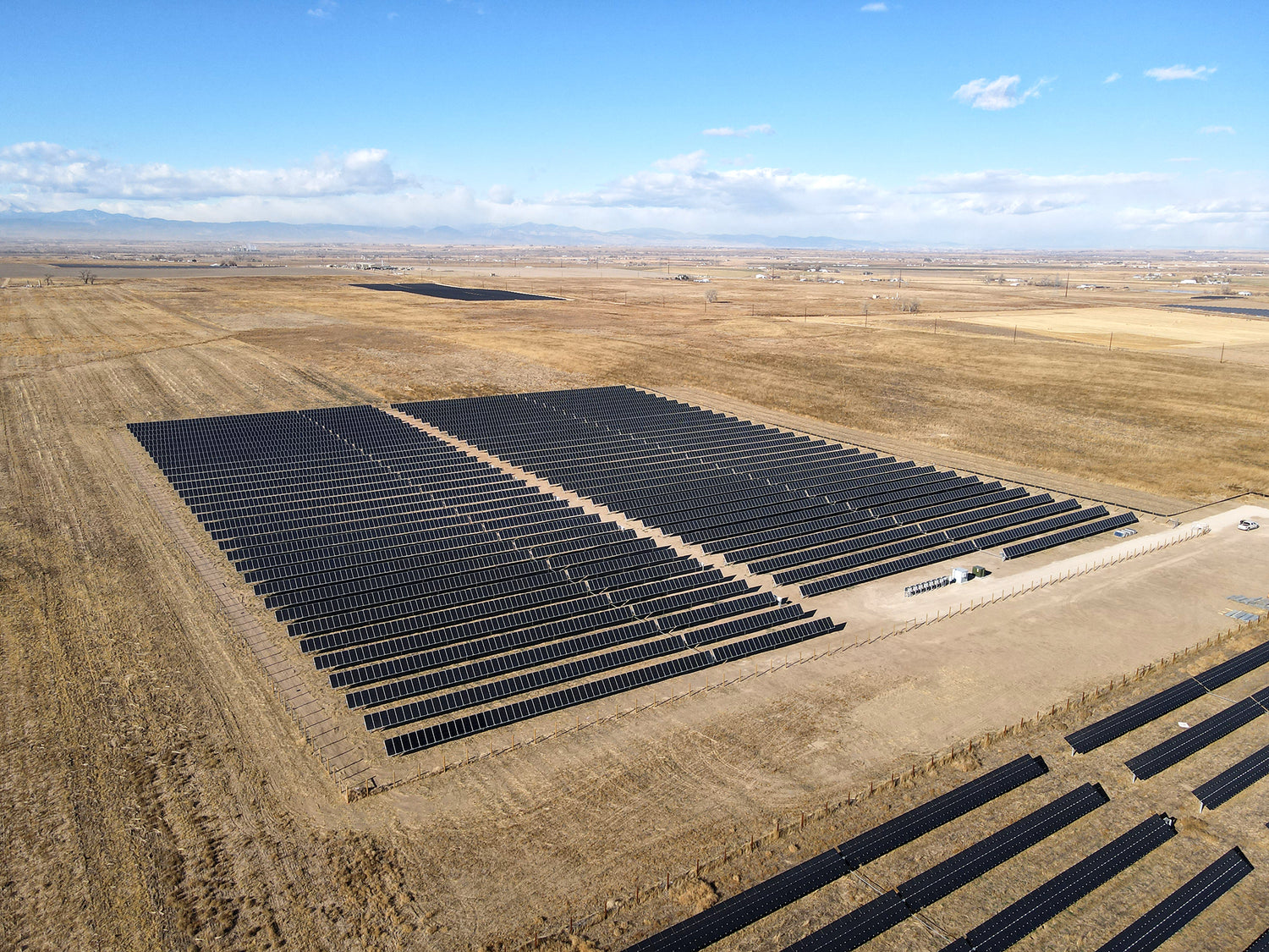 A large solar panel farm in a desert landscape with clear skies.