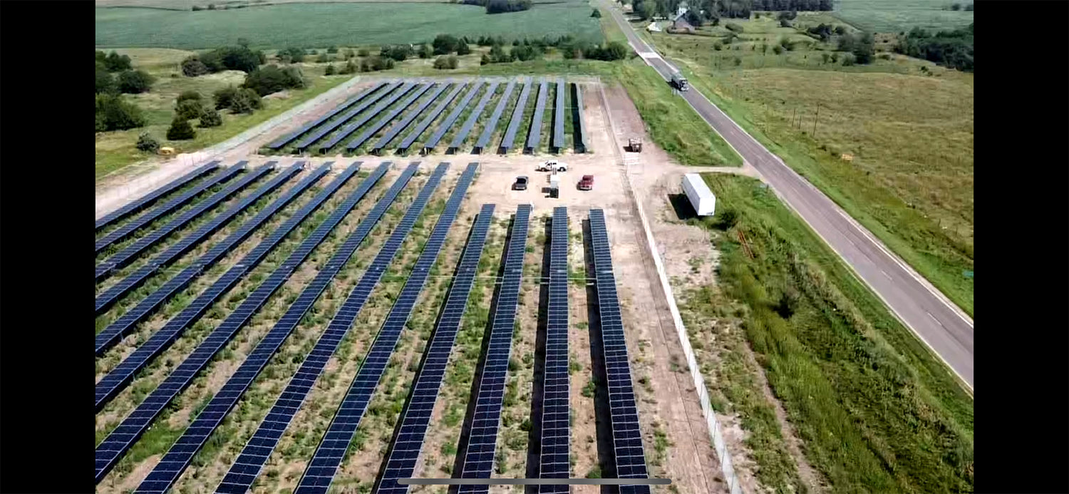 Aerial view of a large solar panel farm in a rural area.