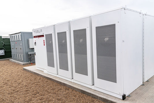 A pod of BESS units on concrete.
They sky above is a grayish white - almost the same color as the BESS units.